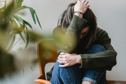 Unrecognizable upset lady embracing knees sitting on chair