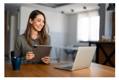 Life coach holding a tablet and looking at a laptop.