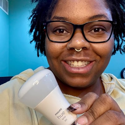 Ashley smiling and holding a philips hue lightbulb