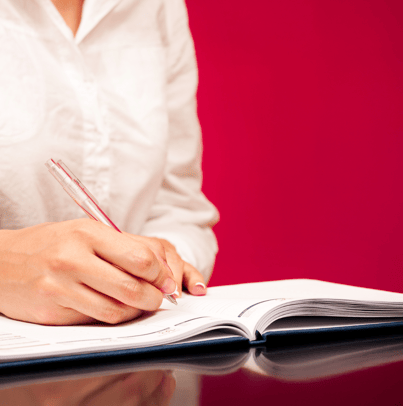 a woman is writing on a notebook with a pen and a pen