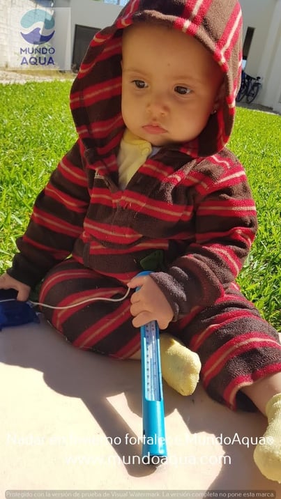 a baby in a striped jacket and a toothbrush