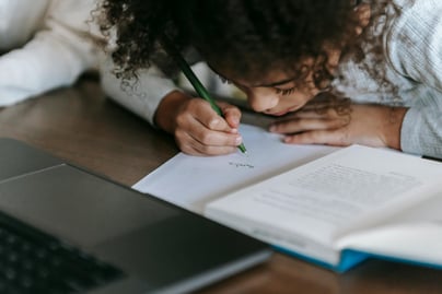 "Small girl writing in a notebook, focused on her learning."