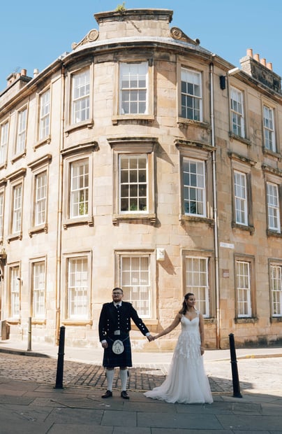 a bride and groom holding hands in front of a building