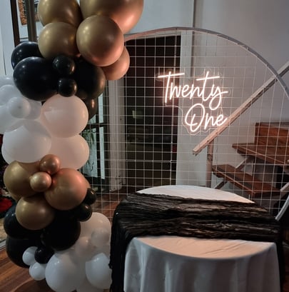 Circle backdrop with a Twenty One neon sign with a black, gold, white balloon garland, Burpengary.