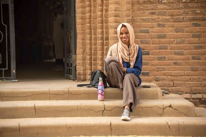 Sudanese student writing on university steps