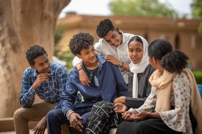 Group of Sudanese university students chatting together under a tree.