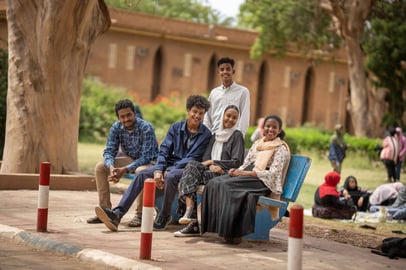 Group of students sitting on a bench on campus in Sudan.