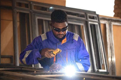 Sudanese welder working with protective gear and welding torch.