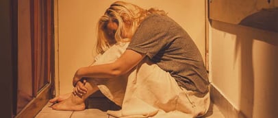 a woman sitting on the floor in a bathroom traumatized