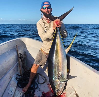 A man holding a Yellowfin Tuna on a boat during a Zanzibar fishing charter, perfect for Zanzibar