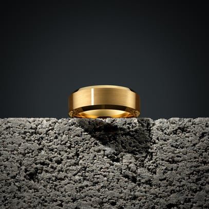 Gold ring on rough concrete surface, dark background, highlighting texture contrast