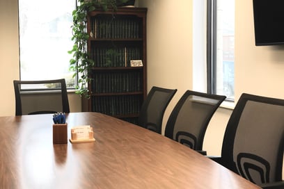 a conference room table with a bookcase and a television