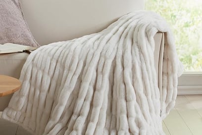 a white couch with a white plush blanket on it