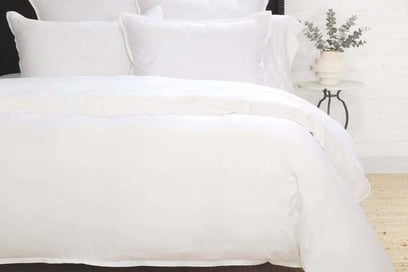 a bed with white sheets and pillows on a bed