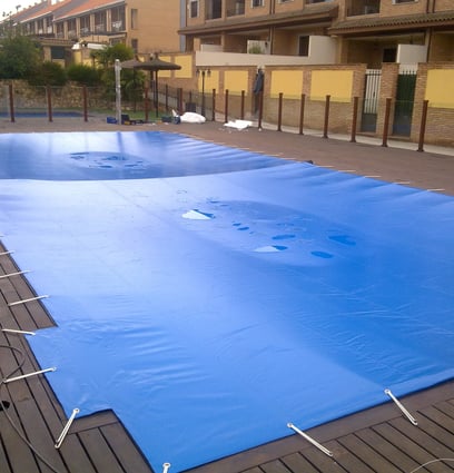 a pool with a blue cover and a tennis court