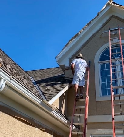 Professional Painter Working on a Large House with Exterior Painting and Rotten Gutter Replacement