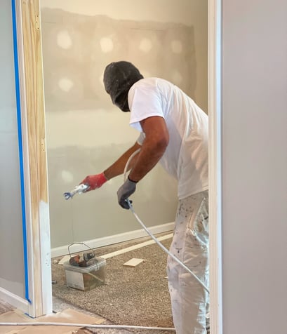 Professional Painter Spraying a Reinstalled Door with a Smooth, High-Quality Finish