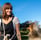 a woman in overalls and overalls sitting on a bench with a dog