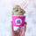 a person holding a cupcake in a pink cup