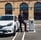 a man in a suit and tie tie standing in front of a car