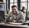 photo d'un homme, il est assis à son bureau et sourit
