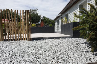 Allée moderne en gravier avec terrasse en dalles et palissade en bois
