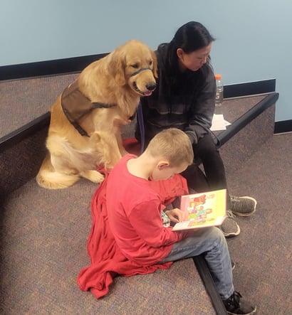 A boy reads to a Tender Paws Therapy Dog Team.