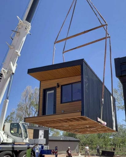 Tiny home pod lifted by crane for easy placement on site