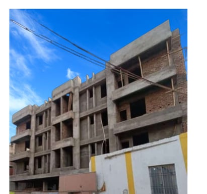 A multi-story residential building under construction, with exposed brick walls and concrete beams.
