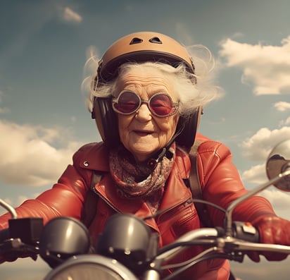 Old woman dressed in a red leather jacket and riding a motorbike.