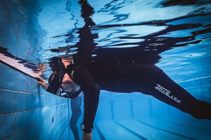 a man in a wetsuit is swimming in a pool