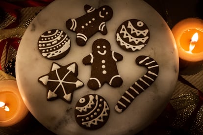 Dimly-lit handmade Christmas cookies, shaped as a Gingerbread Man, a candy cane and Christmas balls