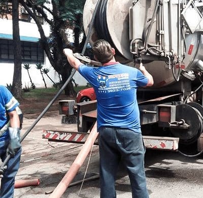 técnico uniformizado e prestando serviço de hidrojateamento com caminhão especializado