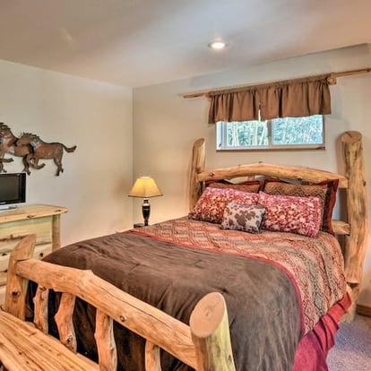 Warm and rustic bedroom with log frame bed, flat-screen TV, and woodsy charm.