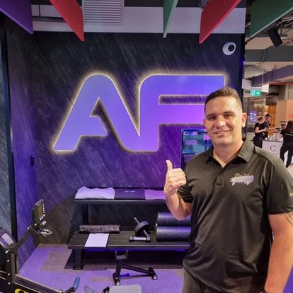 Kahn in front of the AF sign in the gym on grand opening day in Chermside.