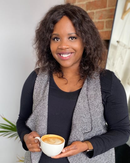 a plus size black woman nutritionist holding a cup of coffee in a room