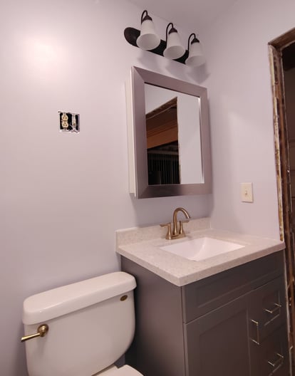 Bathroom remodeling in Goshen, IN with new toilet, new sink, new mirror, and new lighting.