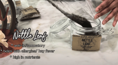 a person is pouring nettle leaf into a jar 