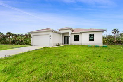 Single-family new construction home with landscaped front yard in Lee County, Florida.