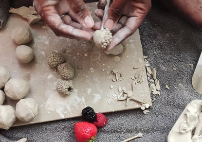 a woman is making clay fruit
