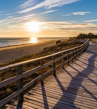a wooden boardwalk with a wooden boardwalk and a sunset