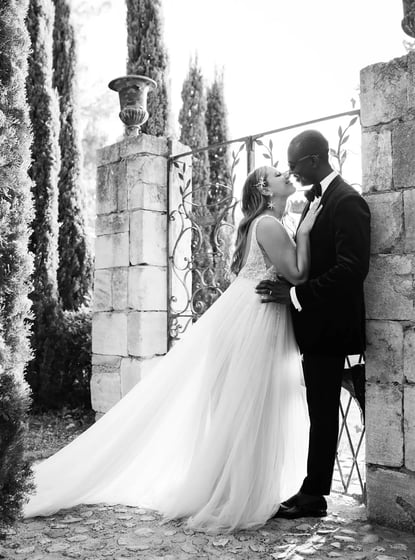 Black and white portrait of newlyweds in a French garden, bride nestled against the groom