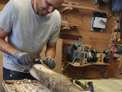 a man is using a sawhorse to strip the bark of a log