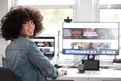 a woman sitting at a desk with a computer and a laptop about to perform a remote online notarization