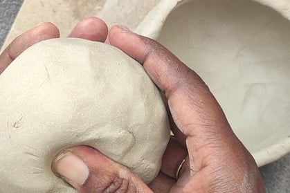 a person shaping a ball of clay in their hands