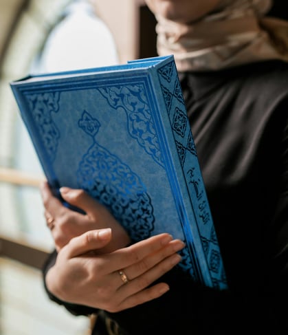 femme serrant un coran bleu contre elle refflètant l'amour de l'apprentissage du coran
