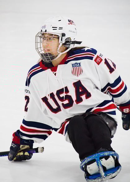 a sled hockey player in a white USA jersey and a hockey helmet