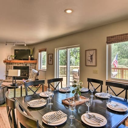 Large dining table set for eight with views of the stone fireplace and walk-out deck.