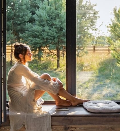 a woman sitting on a window sill meditating