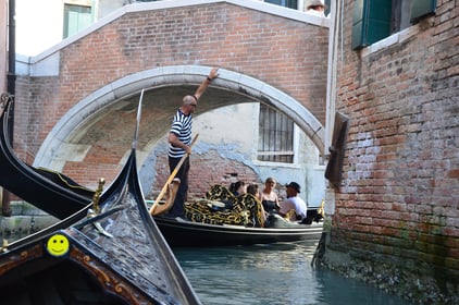 Gondolier steering below a small bridge in Venice, Italy